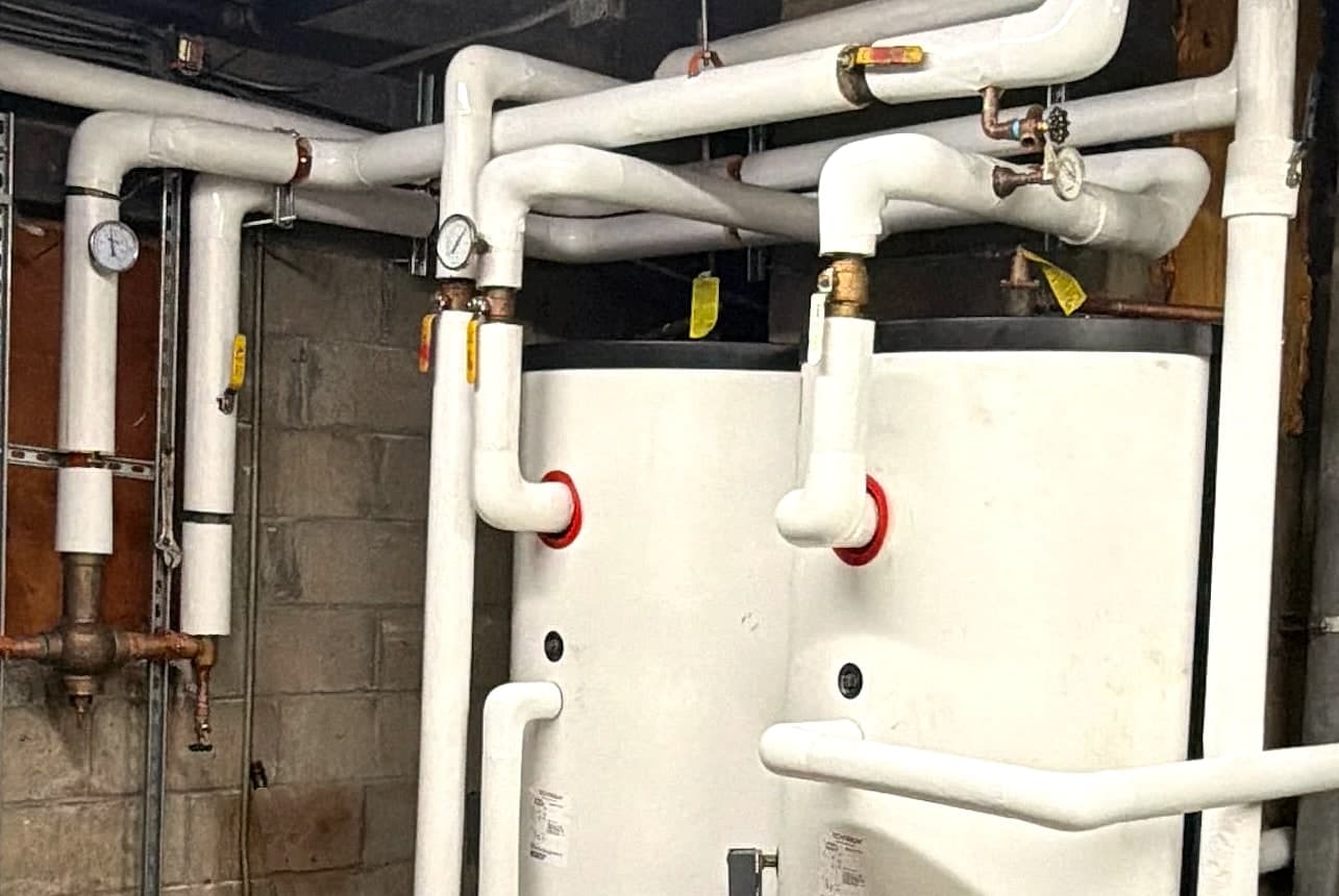 Insulated supply and return piping, gauges and thermostatic mixing valve above the new indirect tanks