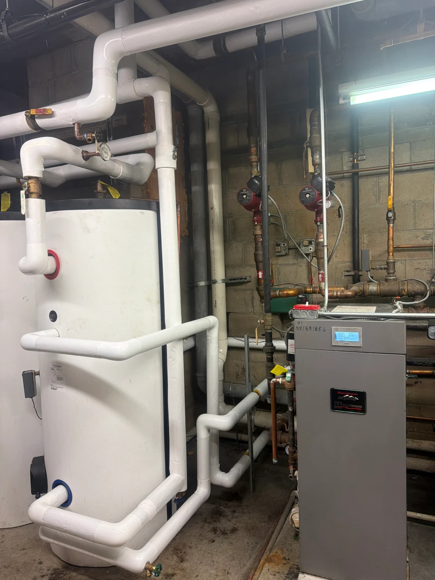New HTP SuperStor Ultra indirect water heater with insulated piping beside the building's Burnham Alpine boiler